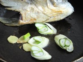 煎鱼的同时放入姜片和葱段一起煎。