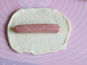 取一个面团，用擀面杖擀开，放入烤肠或者肉松。从上往下卷起，卷成长条形。