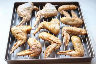 腌好的鸡翅均匀摆在烤架上，烤架放入烤盘。