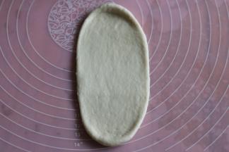 取一个面团，用面杖擀开，拍去面团两侧小气泡。