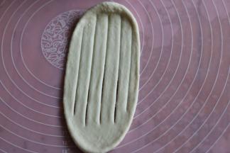 另一个整形，取一个面团擀开，用刮刀在面团上切口，注意两头不要切断。