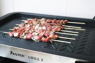 放上穿好的羊肉串开始煎烤。