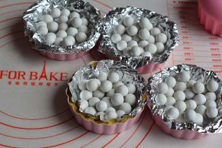 每个挞皮上铺一层锡纸，再撒上烘焙石，防止烤的时候挞皮变形