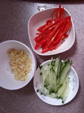 这时把黄瓜切丝。红椒切丝。姜蒜剁成沫。
