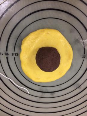 拿一个面团按成中间稍厚一些，四周薄的圆饼，然后将豆沙放在中间