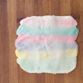 包好后压扁擀成长方形。 按照彩色油酥的方向横向擀开，长度大约20厘米左右。