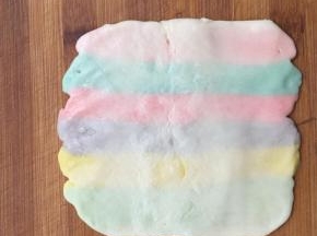 包好后压扁擀成长方形。 按照彩色油酥的方向横向擀开，长度大约20厘米左右。