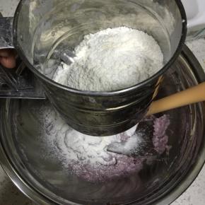 接着用面粉筛将低筋面粉筛入到黄油紫薯中
