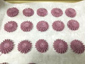 烤盘内铺一张油纸，挤入曲奇面糊，我用的是三能SN7151裱花嘴，在挤入面糊结束时往下顿一下，然后可以用手指轻轻按压一下，把中间的面糊按平整