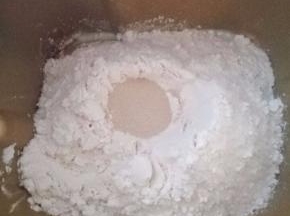 3.加入面包粉，在面包粉上挖个洞，埋入酵母，面包机开始揉面程序。