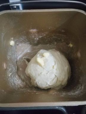 4.待揉成光滑面团后，加入软化的黄油，继续揉面，揉到能拉出大片薄膜为止。