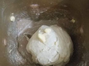 4.待揉成光滑面团后，加入软化的黄油，继续揉面，揉到能拉出大片薄膜为止。