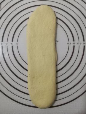 9.将卷竖着擀成比吐司盒略窄的长条状，再滚成卷。