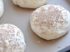 烤箱中放一碗开水，同时把滚圆的面包胚放入，发酵45分钟左右，面团至两倍大。取出面包，表面抹一层水，再散上白芝麻。