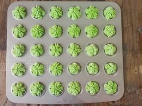 裱花嘴装入裱花袋顶部，面糊装入裱花袋中，垂直对准模具挤出樱花图案