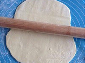 洒少许面粉，压扁后用擀面杖擀成圆形长面片