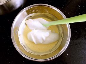 将打好的蛋白霜的一半放入奶酪糊中，搅拌均匀。