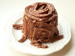 用裱花嘴在杯子蛋糕周围挤出树干的样子，顶部也挤出年轮的样子，底部再留几根树根，随意挤就行。