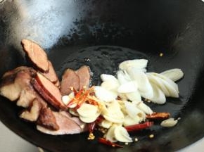 炒锅加入花生油，下入肉片，姜丝葱片蒜片和红辣椒丝。