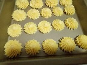 挤入烤盘中，并间隔缝隙，(手法:手握裱花袋，垂直的往下挤，挤到自己想要的大小时停止，将裱花袋转个圈，裱花袋里面饼干糊自然和挤出来的饼干断开)