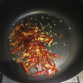 把多余的油倒出来，留一点点在锅内，中火，倒入切丝的干红椒、花椒粒，炒香