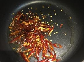 把多余的油倒出来，留一点点在锅内，中火，倒入切丝的干红椒、花椒粒，炒香