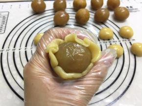 左手抓住月饼底部，右手的虎口从下把面轻轻往上推，边挤边转