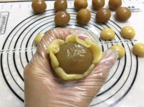 左手抓住月饼底部，右手的虎口从下把面轻轻往上推，边挤边转