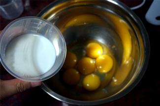 将5个蛋黄，1个全蛋同放入打蛋盘中，分三次加入80克牛奶，用打蛋器搅拌均匀。