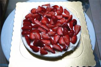 将最底的那片蛋糕片放在底托上，抹上一层淡奶油，然后铺放上草莓粒，多放点水果可以少填些奶油，吃起来更清爽不腻。
13、