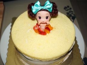 将最后一片中间掏空了的蛋糕片铺放到最表层，然后插入公主娃娃，四周用水果粒填充逼实。
15、