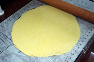 将面团放在硅胶垫中央位置，然后上面盖上保鲜膜，将面团擀成比派盘稍大点的薄片，厚度0.3厘米。