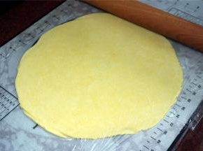 将面团放在硅胶垫中央位置，然后上面盖上保鲜膜，将面团擀成比派盘稍大点的薄片，厚度0.3厘米。