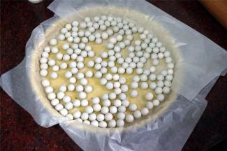 在派皮上垫油纸，放入小圆石，防止烘烤时鼓起。烤箱上下火170度，约烤20分钟取出备用。