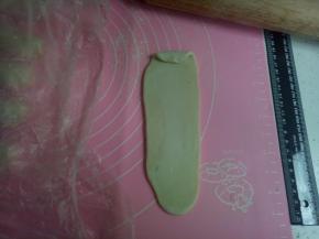 用擀面杖擀，从中间往上一下，往下一下，一上一下，平均轻轻，能拉长点就长点。再从上面往下卷起来，收口向下。再静止15分钟 （冬天30分钟），不拉长后面烤的时候不容易变酥。