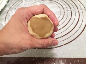 饼皮压成中间稍厚边缘薄的圆片，包住月饼馅，虎口慢慢往上推，收口收紧
