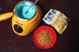 饼干出炉冷却的过程，融化巧克力。往融化了的巧克力酱中加入15克的黄金椰蓉，拌均匀。