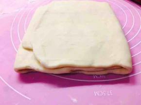 折叠两次后，第三次，将面片擀成成方形后，面片不两头向中间对折了，将一头折于中间位置，另一头折过来压住。将面片折成三折。