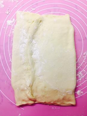 将面片两头折起，将黄油包裹在其中，捏紧接口位置，按压住上下两头