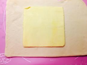 将冷冻过后的面团取出，擀成一个长方形，将冷藏后的黄油片放置在面片中间位置