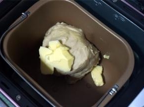 将主料中黄油除外的食材，按照先液体后固体的顺序放入面包机内，启动一个揉面程序，时间20分钟。程序结束后放入24克黄油块，再次启动一个揉面程序20分钟，面团能拉出薄膜即可。