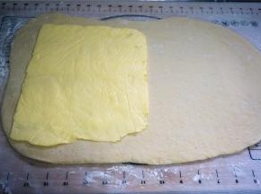 裹入用黄油从冰箱取出，放入小保鲜袋里擀开成薄片状。冷冻的面团取出，擀成黄油片的两倍面积。将黄油片放在面片的左端，折起右端的面皮，覆盖包裹着黄油片。