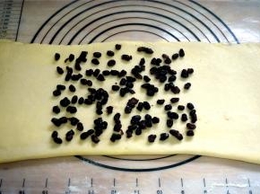 将包裹着黄油的面片擀成长条形，在中间三分之二处放入适量的蜜红豆，然后盖上左端的三分之一面片，再在其上撒上适量的蜜红豆，最后盖上右端三分之一的面片。将折叠好的面片放入冰箱冷冻10分钟。