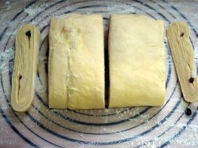 取出冷冻完毕的面团，裁去两边缘面团，然后将面团压开，然后两片长方形面团重叠在一起。