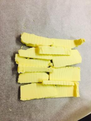 取一张油纸，将黄油放置于上，折叠起油纸四边，包裹起黄油的同时，折叠的出你想要的大小