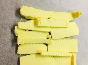 取一张油纸，将黄油放置于上，折叠起油纸四边，包裹起黄油的同时，折叠的出你想要的大小