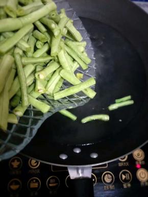 取一干净的锅，倒入清水，待水烧开后倒入豇豆；