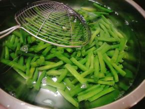 接着准备洗干净的容器，倒入凉水，将豇豆捞出放进容器里过水；