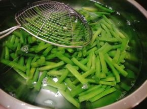 接着准备洗干净的容器，倒入凉水，将豇豆捞出放进容器里过水；