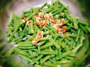 然后将煸香的蒜、姜末、朝天椒圈、花椒复合油浇在豇豆上；